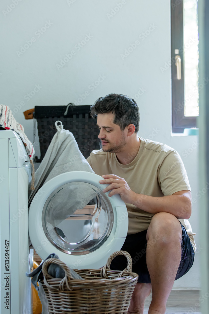 man put clothes into the washing machine at home man put clothes into the washing machine at home