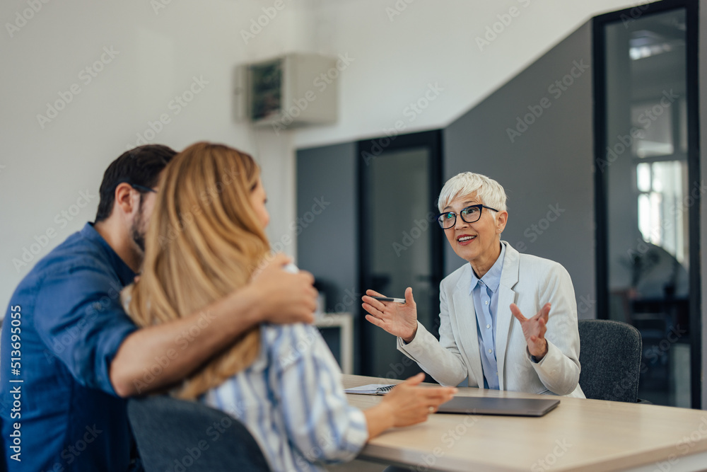 Couple consulting with an older businesswoman, working as the insurance agent.