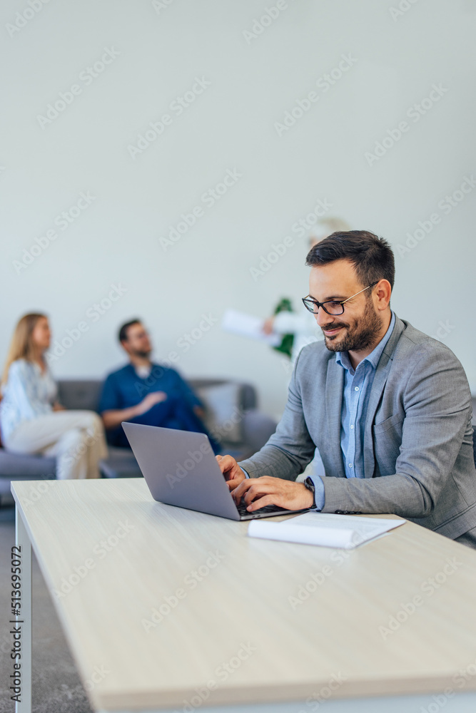 Focus on the businessman working over the laptop, and people sitting in the background. Focus on the businessman working over the laptop, and people sitting in the background.