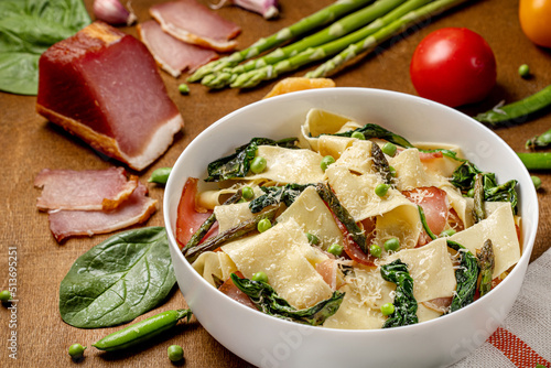 Pasta pappardelle with Italian prosciutto or jamon and spinach, parmesane, asparagus . Wooden background. Close up. photo