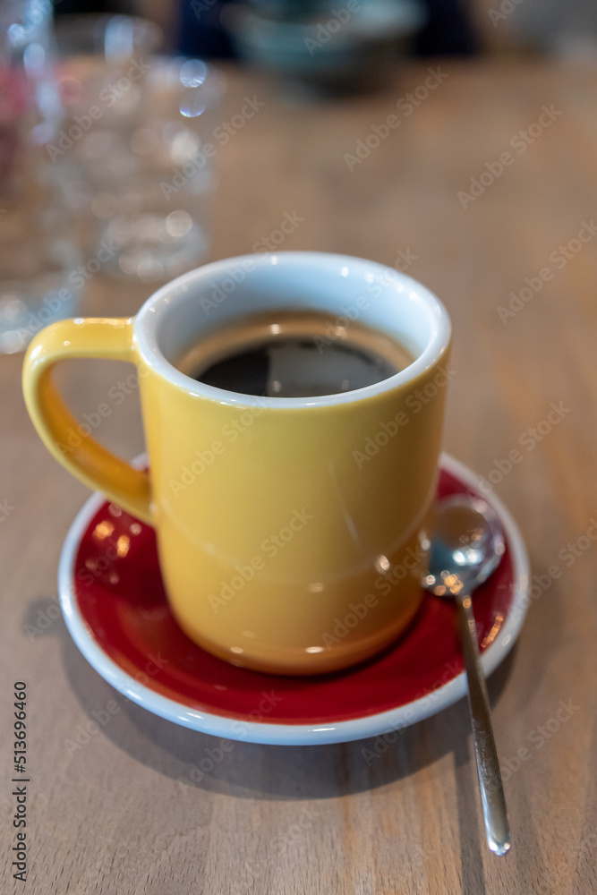 a yellow mug morning coffee on a red saucer on the table