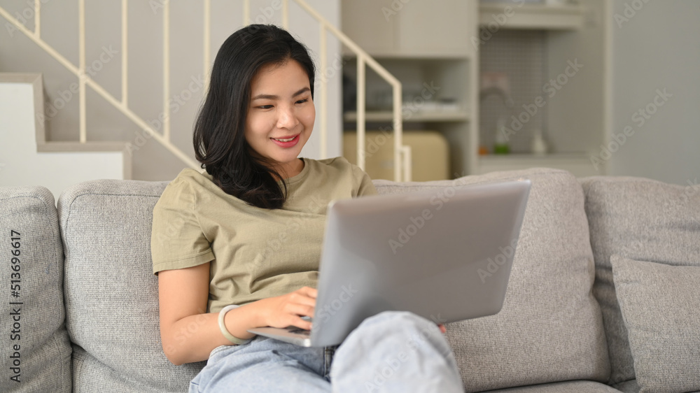 Charming asian woman in casual clothes surfing internet, reading online new on laptop at home Charming asian woman in casual clothes surfing internet, reading online new on laptop at home