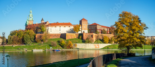 Krakow, Poland. Panorama with Royal Wawel castle and cathedral, Vistula river, promenades and an autumn tree in sunset light