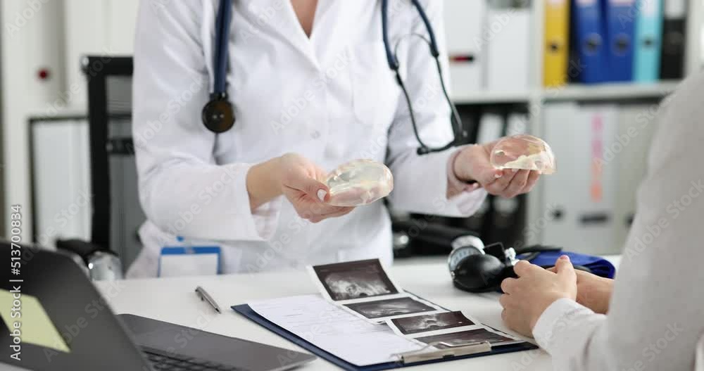 Doctor shows silicone implants for breast augmentation to patient in clinic closeup Doctor shows silicone implants for breast augmentation to patient in clinic closeup
