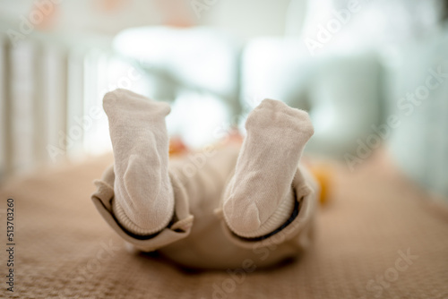 The feet in the socks of a newborn baby lying in the bed