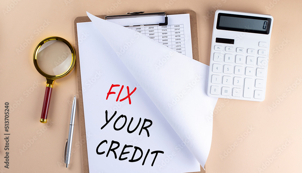 Clipboard with chart and text FIX YOUR CREDIT with magnifier ,calculator on beige background Clipboard with chart and text FIX YOUR CREDIT with magnifier ,calculator on beige background