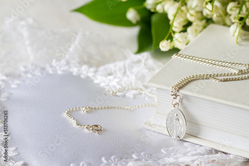 First Holy Communion with sacred medal on chain and flowers, concept background 