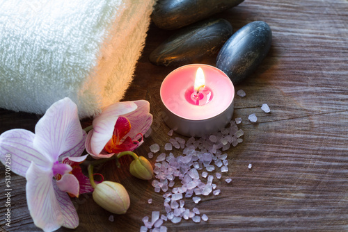 Bath salt  candle  massage stones  towel and orchid on wooden background  spa concept