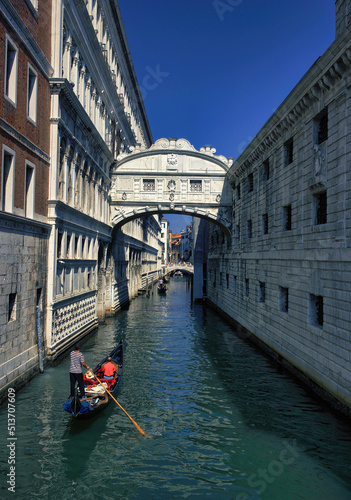 Venice, Italy - September 05, 2018: A man rowing gondola boat with passengers on a green water canal through famous bridge of sigh during day © Arpan