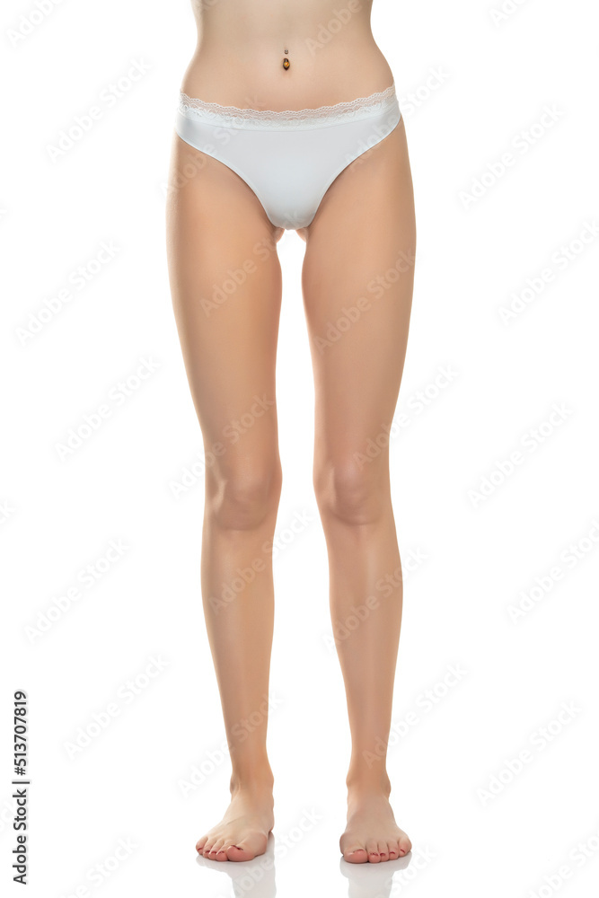 Front view of female barefoot legs in white bikini panties on a white studio background Front view of female barefoot legs in white bikini panties on a white studio background