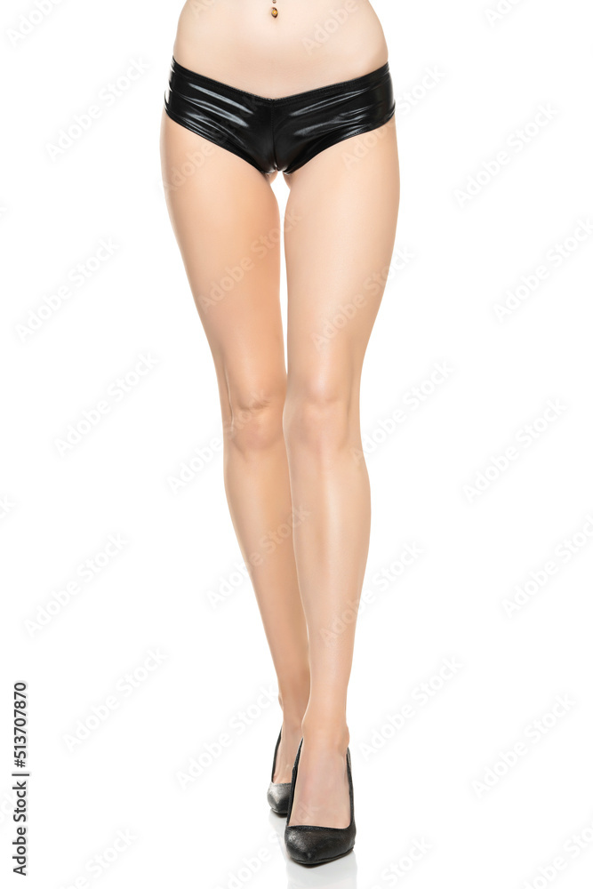 Front view of female barefoot legs in black latex bikini panties and high heels on a white studio background