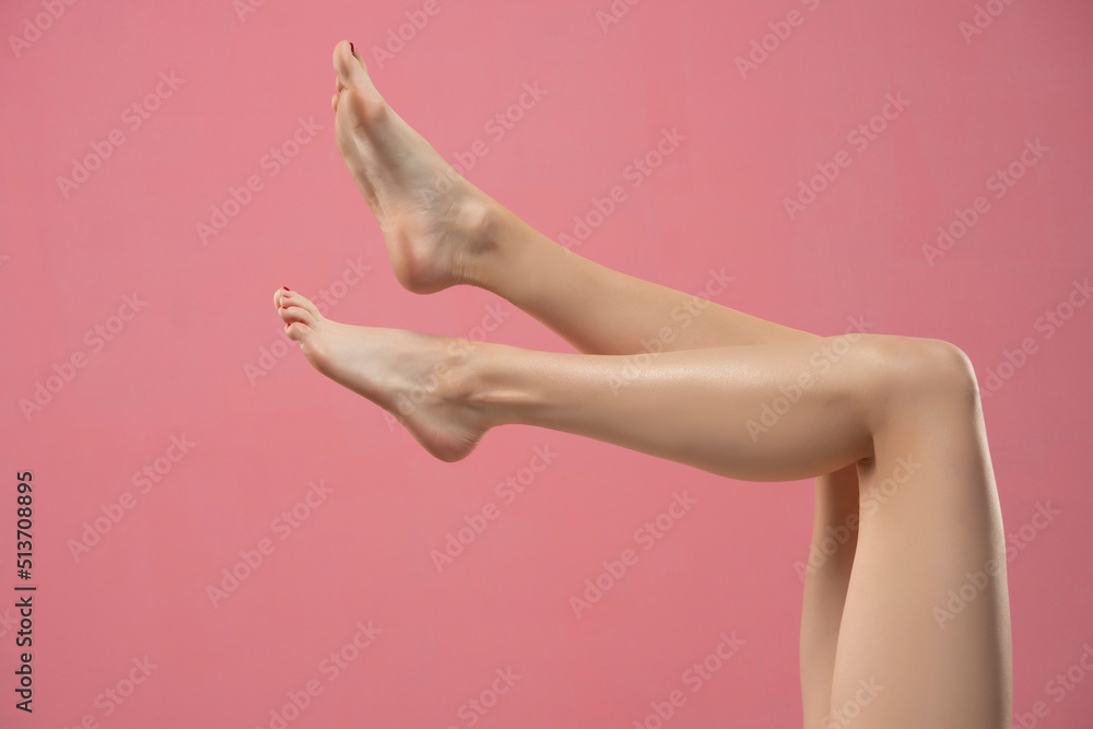 Long pretty smooth woman legs isolated on pink background