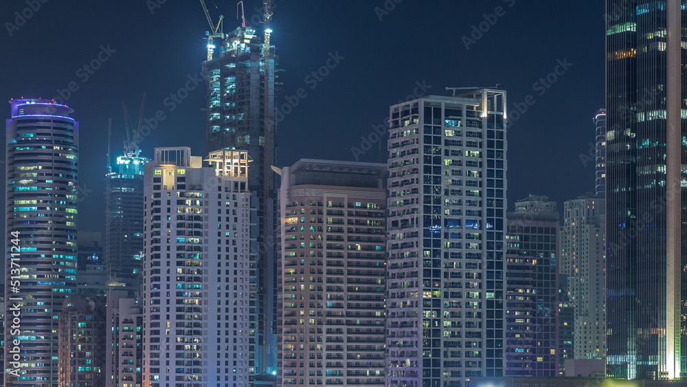 Dubai Marina skyscrapers and Sheikh Zayed road with metro railway aerial night timelapse, United Arab Emirates