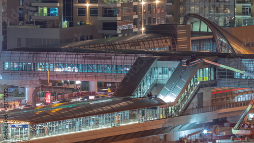Futuristic building of Dubai tram station and luxury skyscrapers behind in Dubai Marina aerial night timelapse © neiezhmakov