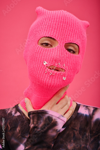 Portrait of young woman wearing pink balaclava with sewed mouth having no rights to speak