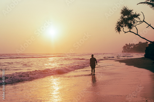 Male model  traveler walking the beach with sunset and ocean background  holiday tropical landscape.