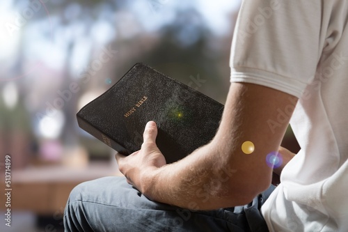 Human with a Bible in his hand during a sermon. The preacher delivers