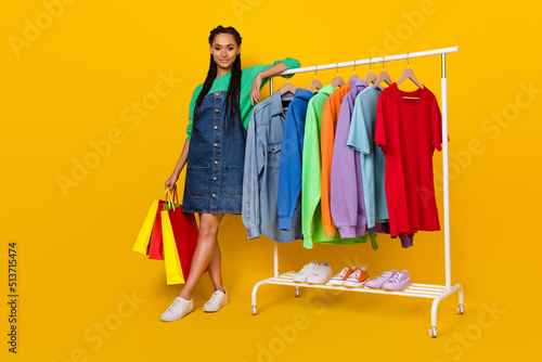 Full length portrait of pretty positive person hold packages choose assortment isolated on yellow color background