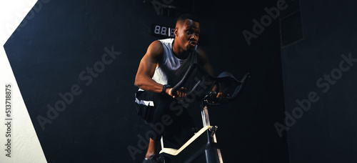 Fotografia Sporty African-american man cardio with exercise bike burning calories with in the fitness gym fit body healthy lifestyle, Athlete muscle building strong concept