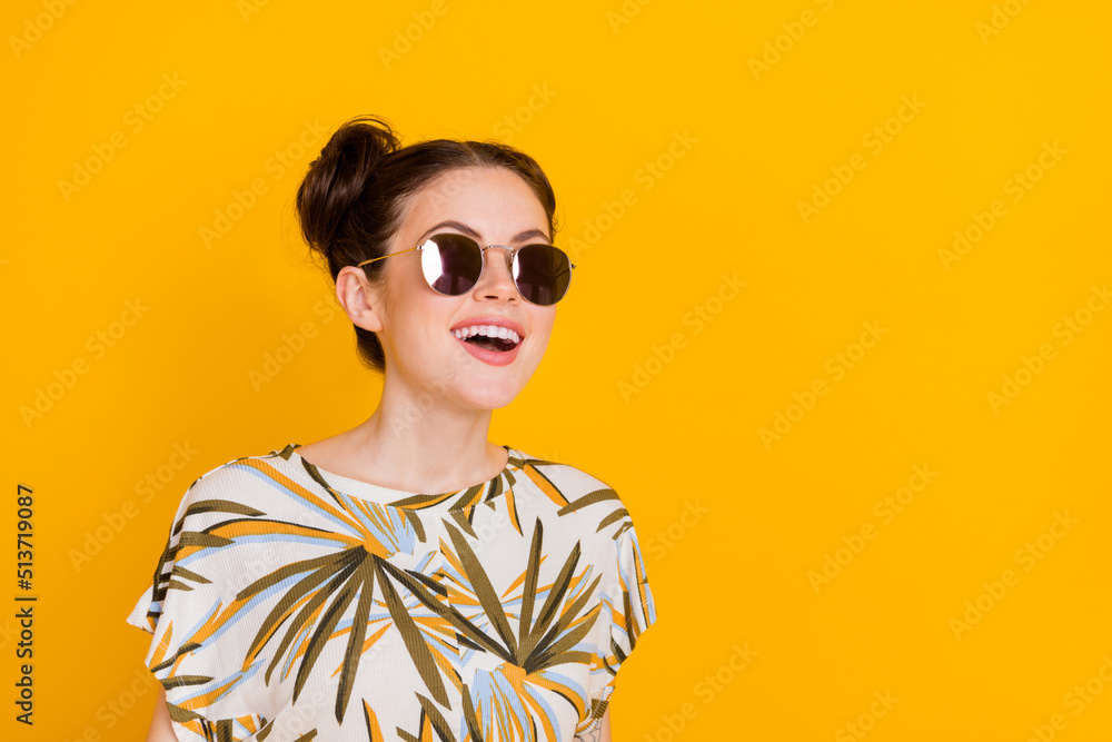 Photo of cute excited lady dressed print t-shirt dark glasses looking empty space isolated yellow color background Photo of cute excited lady dressed print t-shirt dark glasses looking empty space isolated yellow color background