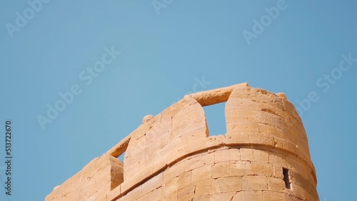 Closeup shot of carved and decorated walls of the Jaisalmer Fort at Rajasthan in India. Carved walls in front of the clear blue sky. Walls made out of sandstone. Ancient architecture of India.	 photo