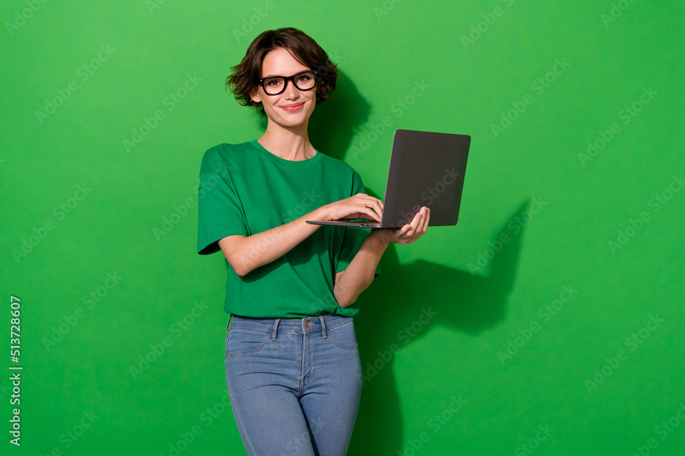 Photo of smart clever woman wear casual t-shirt spectacles typing modern device isolated green color background Photo of smart clever woman wear casual t-shirt spectacles typing modern device isolated green color background