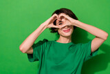 Photo of funny adorable young lady dressed casual t-shirt smiling showing fingers heart isolated green color background