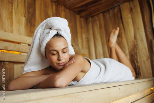Satisfied woman with eyes closed lies in the sauna at spa