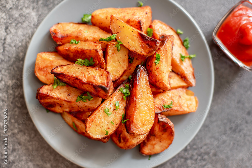 Baked potato wedges with herbs and sauce on stone background - homemade organic vegetable veggie veggie potato wedge appetizer.