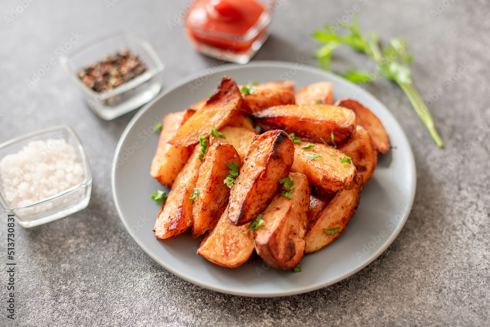 Baked potato wedges with herbs and sauce on stone background - homemade organic vegetable veggie veggie potato wedge appetizer. Baked potato wedges with herbs and sauce on stone background - homemade organic vegetable veggie veggie potato wedge appetizer.