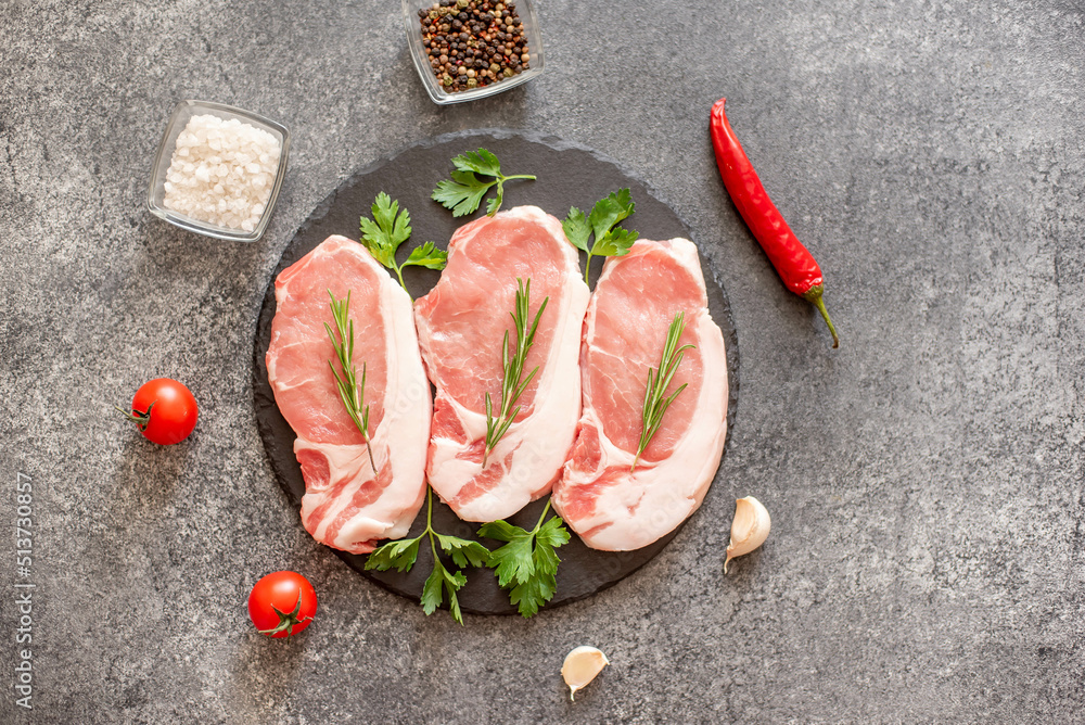 raw pork steaks with spices on a stone background raw pork steaks with spices on a stone background