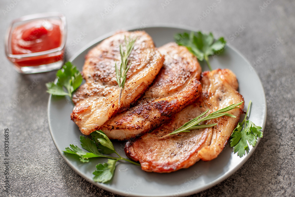 grilled pork steaks with spices on stone background