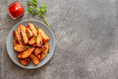 Baked potato wedges with herbs and sauce on stone background - homemade organic vegetable veggie veggie potato wedge appetizer with copy space for your text