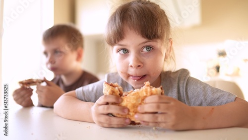 children eat fun burgers. fast food burger. a group of small children in the kitchen greedily eat fast food burgers. big family small kids having breakfast in the morning in the kitchen eating burger