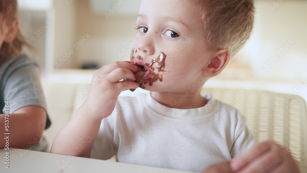 children eat chocolate. dirty little baby kids in the kitchen eating chocolate in the morning. happy family eating lifestyle sweets kid dream concept. baby dirty face eating chocolate cocoa children eat chocolate. dirty little baby kids in the kitchen eating chocolate in the morning. happy family eating lifestyle sweets kid dream concept. baby dirty face eating chocolate cocoa
