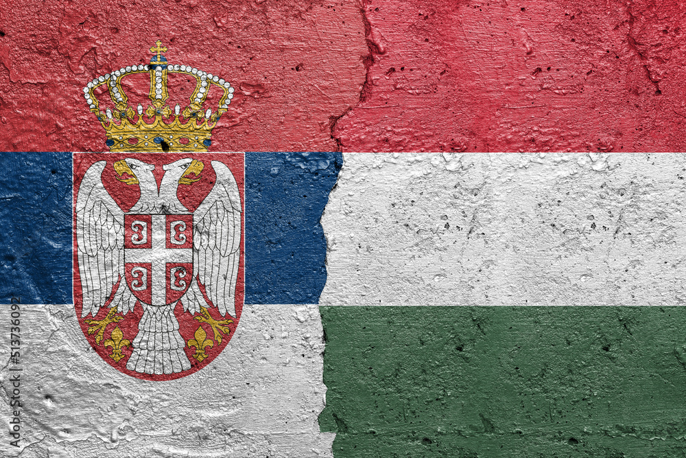 Serbia and Hungary - Cracked concrete wall painted with a Serbian flag on the left and a Hungarian flag on the right stock photo