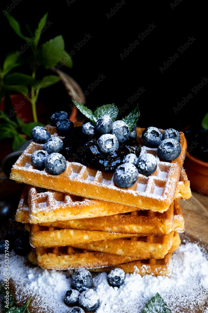 Waffles with fresh blueberries and powdered sugar on the rustic table. Freshly made Belgian waffles