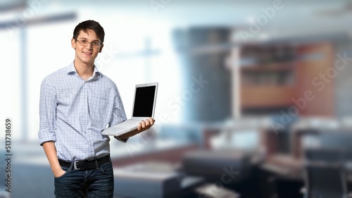 Happy young freelancer guy with laptop working online and browsing internet on blue background.