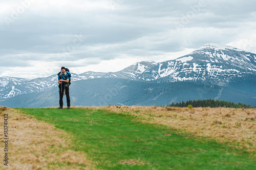 Canvas Print young boy man with a large tourist hiking trekking backpack stands against the b