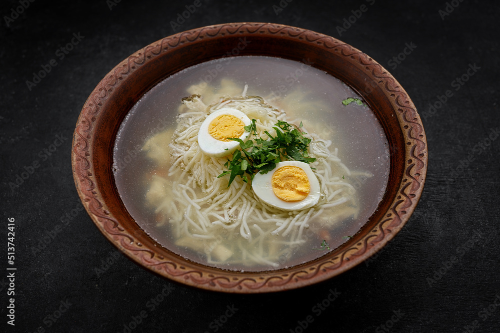 Chicken broth, with noodles, herbs and egg, studio light Chicken broth, with noodles, herbs and egg, studio light