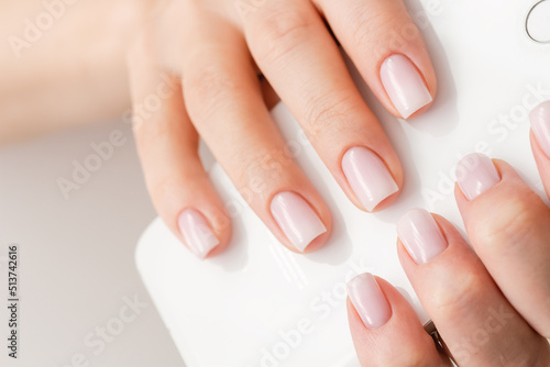 Female hands with beautiful nails with stylish trendy nude manicure.