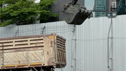 4K Slow motionn, A large backhoe is shoveling black soil into a large truck to be dumped elsewhere on a construction site to prepare for digging. photo