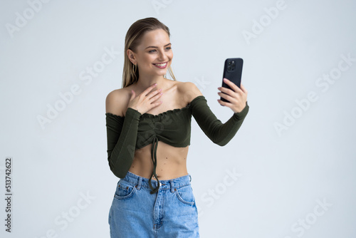 Portrait of a shocked young woman looking at mobile phone isolated over white background