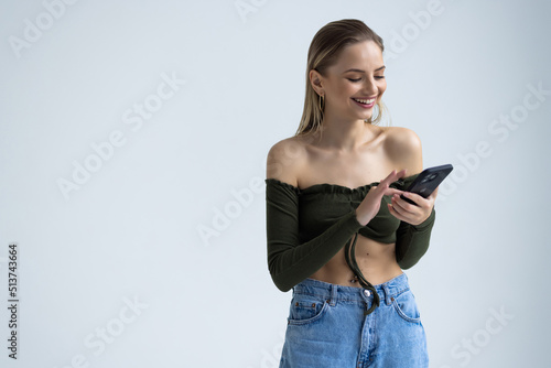 Young woman posing isolated over white wall background using mobile phone.