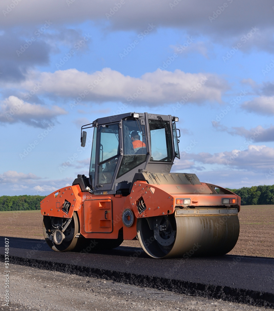 roller laying fresh asphalt . Road works with excavators. Construction of new roads on the highway in the field 