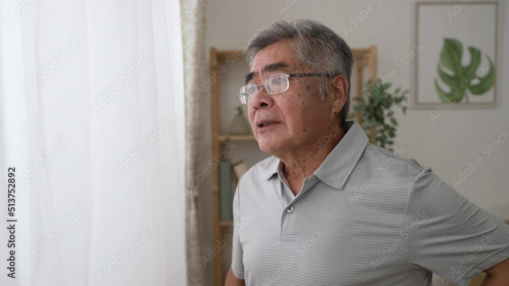 Side view thoughtful middle aged mature grandfather standing by window looking away. Pondering asian old senior hoary man think of psychological health problems spend time alone at home Side view thoughtful middle aged mature grandfather standing by window looking away. Pondering asian old senior hoary man think of psychological health problems spend time alone at home