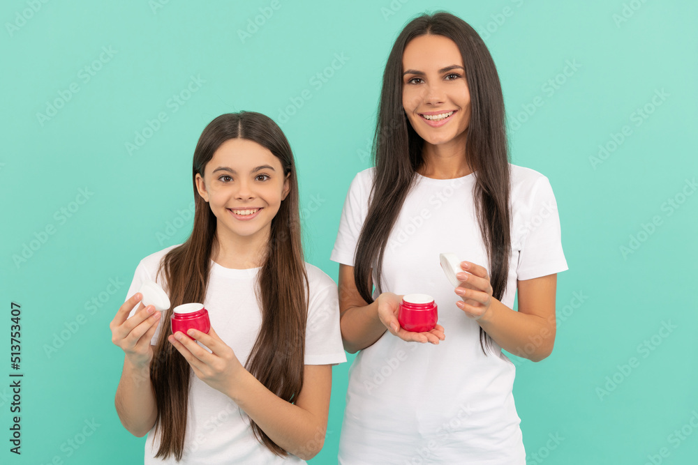 cheerful mother and daughter hold cream jar on blue background cheerful mother and daughter hold cream jar on blue background