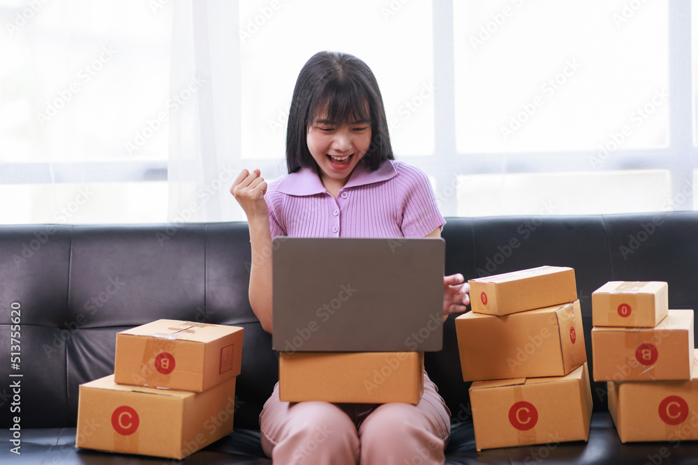 Startup SME small business entrepreneur of freelance using a laptop with box, Asian business woman on sofa check online orders to prepare to pack the boxes sell to customers sme business ideas online. Startup SME small business entrepreneur of freelance using a laptop with box, Asian business woman on sofa check online orders to prepare to pack the boxes sell to customers sme business ideas online.