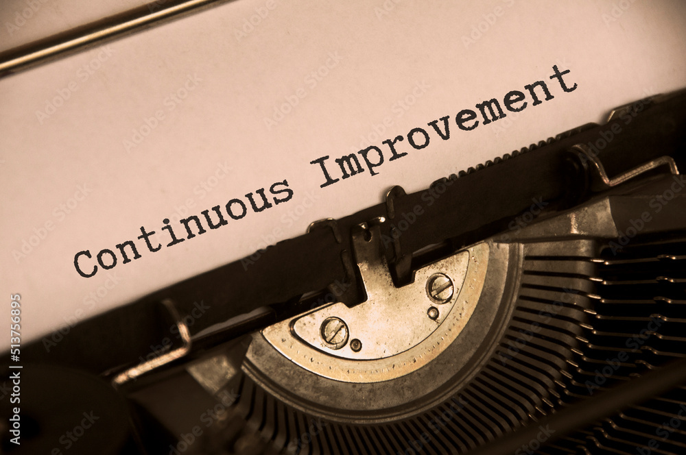 Side view of continuous improvement text on an old typewriter in vintage color. Business concept