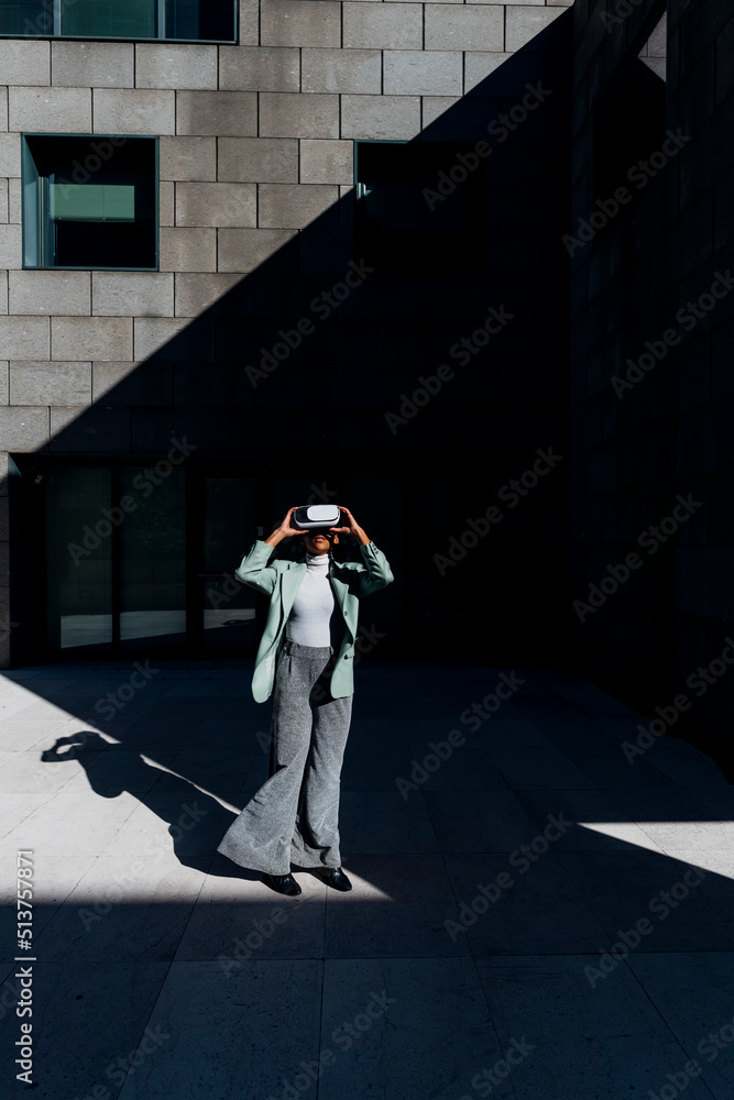 © VISTA by Westend61 - Young businesswoman wearing VR goggles in front of office building © VISTA by Westend61 - Young businesswoman wearing VR goggles in front of office building
